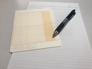 通帳とレポート用紙とペン